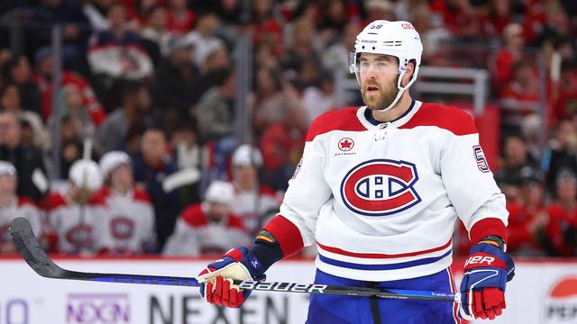 Un hockeyeur tient son bâton à deux mains sur la glace.