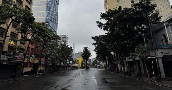 Unter einem wolkenverhangenen Himmel sind menschenleere Straßen zu sehen. Die hohen Häuser und breiten Strassen legen nahe, dass es sich um eine Innenstadt handelt.