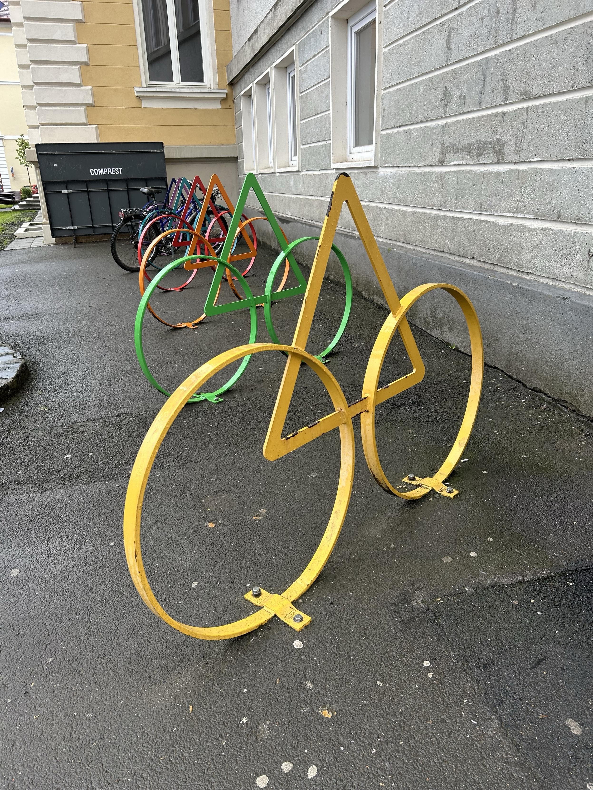 Colorful bicycle racks in the shape of circles and triangles That Build a bicycle, located beside a building. A few bicycles are parked in the background.

Bunte Fahrradständer in Form von Kreisen und Dreiecken, die ein Fahrrad bauen, das sich neben einem Gebäude befindet. Ein paar Fahrräder sind im Hintergrund geparkt.