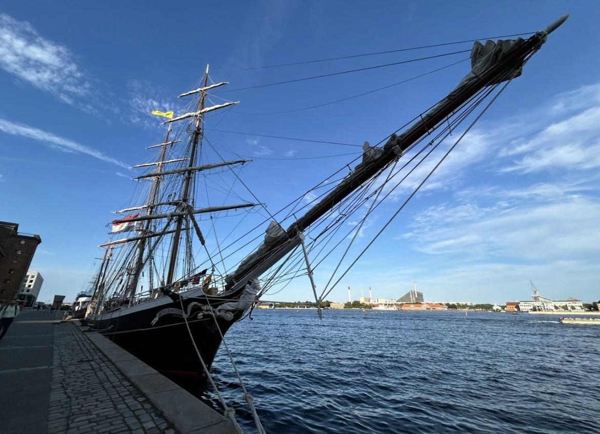 A historic sailing ship docked alongside a waterfront, featuring tall masts, rigging, and a clear blue sky. The ship is moored near a cobblestone walkway, with buildings and distant cityscape visible in the background.
Ein historisches Segelschiff lag an einer Uferpromenade mit hohen Masten, Takelen und einem klaren blauen Himmel. Das Schiff liegt in der Nähe eines gepflasterten Gehwegs fest, mit Gebäuden und einem entfernten Stadtbild im Hintergrund. A historic sailing ship docked alongside a waterfront, featuring tall masts, rigging, and a clear blue sky. The ship is moored near a cobblestone walkway, with buildings and distant cityscape visible in the background.
Ein historisches Segelschiff lag an einer Uferpromenade mit hohen Masten, Takelen und einem klaren blauen Himmel. Das Schiff liegt in der Nähe eines gepflasterten Gehwegs fest, mit Gebäuden und einem entfernten Stadtbild im Hintergrund.