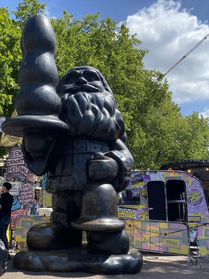 Statue von Person Motivation, welches eine stilisierten Weihnachtsbaum in einer Hand hält, der einen Butt Plug ähnelt