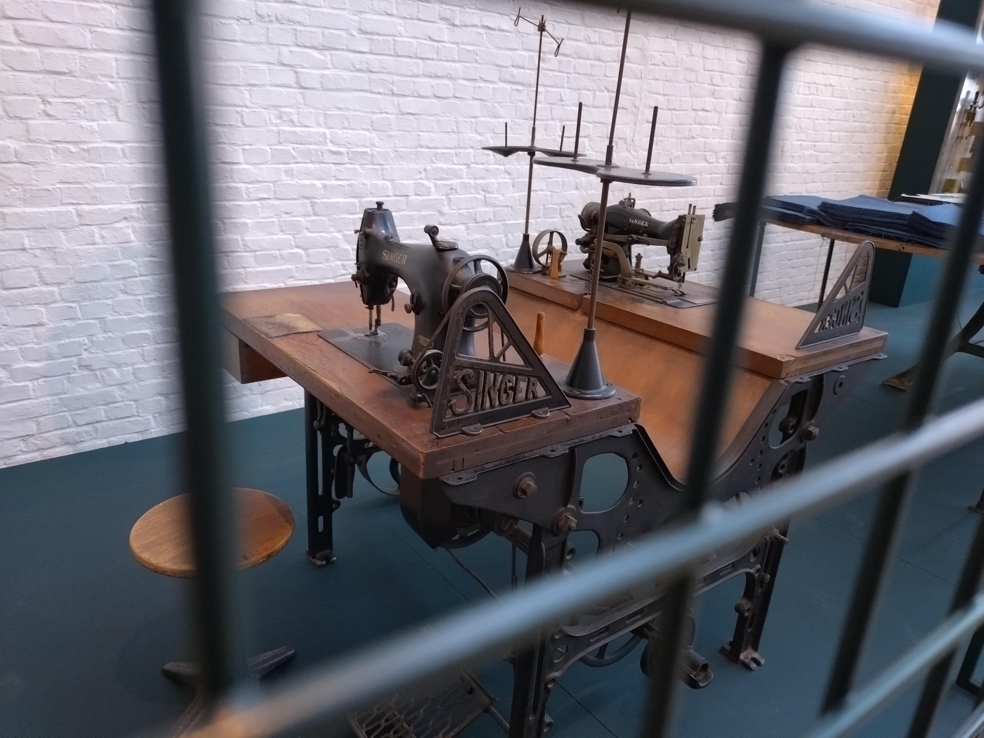 Eine alte Nähmaschine in einem Industriemuseum durch einen Zaun aufgenommen. Eine alte Nähmaschine in einem Industriemuseum durch einen Zaun aufgenommen.