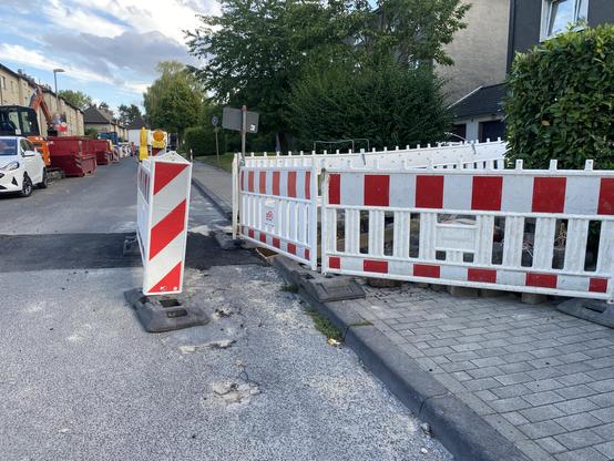 Eine Baustellenabsicherung an einem Gehweg. Die Baustelle ist nur mangelhaft abgesichert. Es fehlt eine Rampe, die es ermöglicht am Bordstein herunterzukommen.