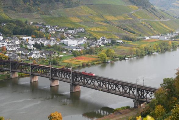 Foto einer doppelstöckigen Brücke über einen Fluss. Oben fährt ein Zug. Unten Auto-, Radverkehr und Zufußgehende.